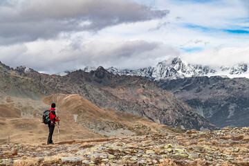 Hiker in the mountains with Bernina massif on the horizon, Valmalenco, Italy landscape
