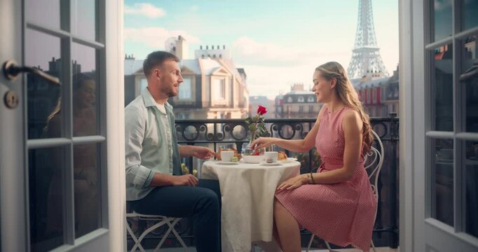 Young Couple Having a Romantic Breakfast with Croissants and Coffee on a Balcony in Paris, Soaking in the Eiffel Tower View. Their Intimate Morning Together is Filled with Love and Warmth