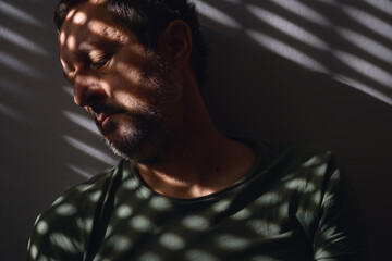 Tired mature adult male sleeping in sitting position while leaning his head against the wall of the dark room