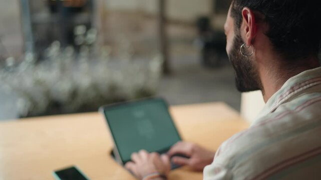 Man looking at tablet screen, appearing to reset forgotten password. modern security practices, with emphasis on personal data protection and secure digital access in public spaces
