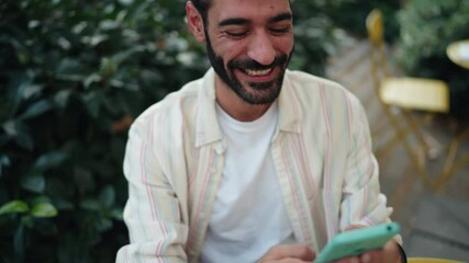 Hispanic man smiling while texts friends on mobile app, enjoying casual communication. ease of digital connections and joy of staying in touch through technology. Typing answer in online chat
