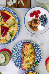 varied breakfast with spanish omelette, yogurt with granola, egg and tomato toast.