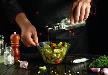Adding vegetable oil to vegetable mix. Chef prepares delicious vegetable salad on kitchen table.