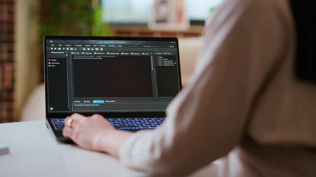 Asian female programmer works on coding software in a home office setup, typing code on a laptop. IT expert uses digital tools for multitasking, software development and app development. Camera B.