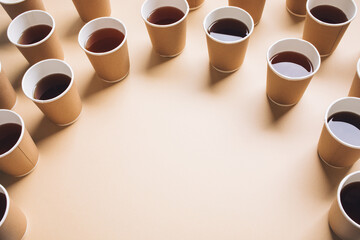 Multiple of coffee takeaway or black tea from an arrangement of paper cups on a beige...