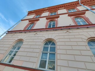 A well-preserved classical building featuring decorative elements and a light blue exterior, set against a bright blue sky. The design embodies timeless elegance and urban heritage.