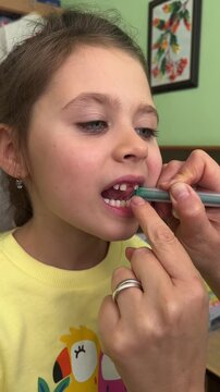 the girl does exercises with a speech therapist, lip and tongue exercises, vertical video