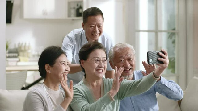 group of happy senior asian people two couples waving hands while video chatting with friends