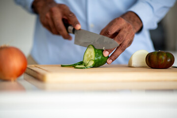 Close-up of hands cutting cucumber on wooden board