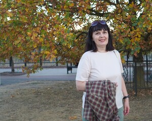 Walk with smiling woman with plaid shirt in hands on background of yellow leaves on oak tree...