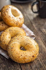 Bagel sprinkled with fried onion, sesame and poppy seeds on wooden table.