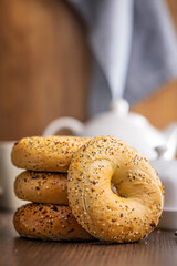 Bagel sprinkled with fried onion, sesame and poppy seeds on wooden table.