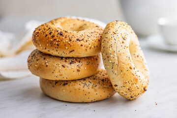 Bagel sprinkled with fried onion, sesame and poppy seeds on kitchen table.