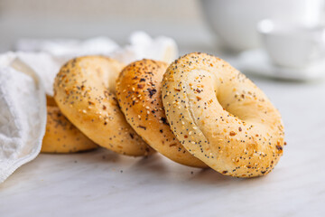 Bagel sprinkled with fried onion, sesame and poppy seeds on kitchen table.