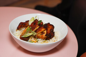 A plate of delicious honey chicken wings `on a wooden pink kitchen table restaurant style gourmet food