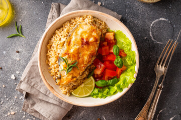 Fried catfish steak with rice and vegetable salad on a gray background