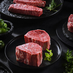 Fresh beef and lamb cuts laid out on a kitchen table, dark background, close-up image of meat