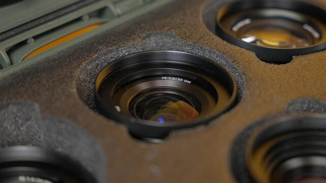 Slow zoom-in shot of a camera lens inside a padded foam case, focusing on the top glass element and metal ring