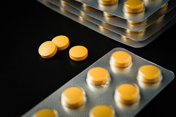 Antipyretic analgesic pills Medicine tablet Brown Yellow in blister pack on a black background