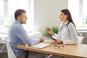 Obraz premium Female doctor or nurse have consultation with a male patient in a hospital office. Physician provides medical advice and conversation, for patient healthcare needs in a professional clinic setting.