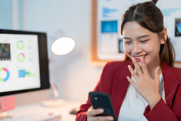 Happy businesswoman working late at the office. Smiling while reading good news on her mobile phone