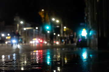 Fototapeta premium A rainy night in the city, with shop window reflections shimmering on the wet pavement. 