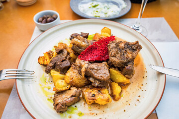 Lamb Tsigaristo, traditional cretan cuisine, stewed lamb piece with fried potato on plate.