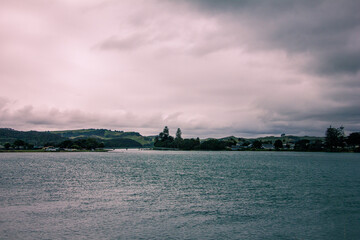 Obraz premium Retro style photo of a breathtakingly serene view of the lake under beautiful, cloudy skies. Raglan, New Zealand. Toned image