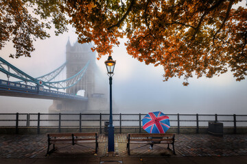 London in autumn concept with a tourist holding a british flag umbrella in front of the famous...