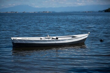 White wooden boat on a calm lake with mountain background