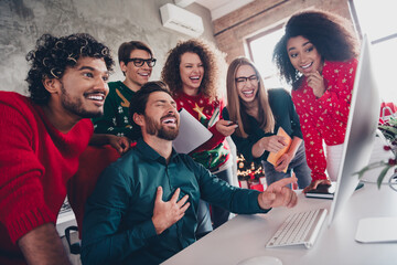 Photo of six corporate workers computer desk laughing point finger monitor xmas atmosphere office party indoors