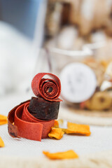 Freshly rolled, homemade fruit leather and dried fruit slices made from organic ingredients are displayed on a rustic table