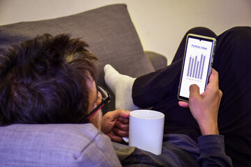 A South Asian Man checking his Portfolio Value on the mobile phone. Asset management, investment concept. Indoor lifestyle.