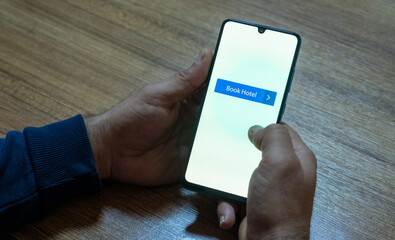 Close-up of the “Book Now” message on the smartphone screen. Online booking concept. Office background. Early booking message. 