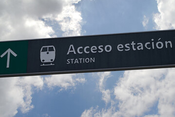 Panneau en espagnol indiquant la direction de la gare de Cadix sur fond de ciel et de nuages