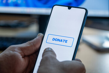 Close-up of “Donate” message on smartphone screen. Online donation concept. Office background. Donate message. 