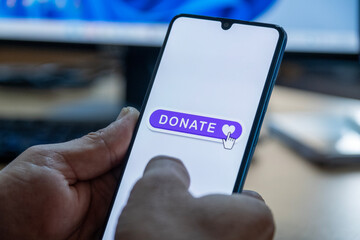 Close-up of “Donate” message on smartphone screen. Online donation concept. Office background. Donate message. 