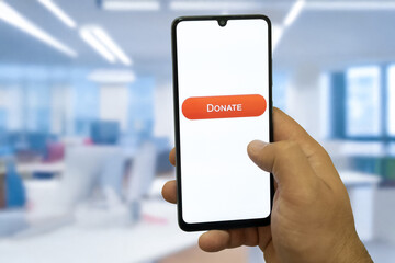 Close-up of “Donate” message on smartphone screen. Online donation concept. Office background....