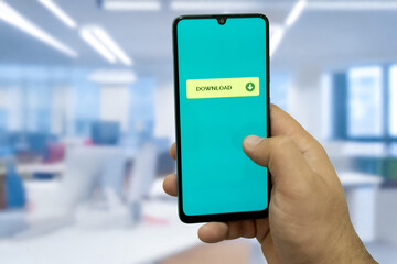 Close-up of “Download” message on smartphone screen. Online file download concept. Office background. Download message. 