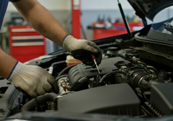 Fototapeta premium Mechanic working on an engine in an auto repair shop with focus on hand tools and vehicle components