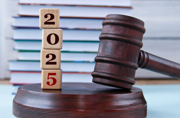 Figures of the year 2025 on wooden cubes against the background of the judge's hammer and stand
