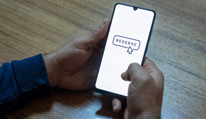 “Reserved” message on close-up smartphone screen. Online reservation. Office background. Hotel, vacation or event booking message. 