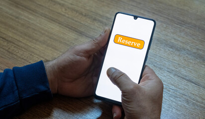“Reserved” message on close-up smartphone screen. Online reservation. Office background. Hotel, vacation or event booking message. 