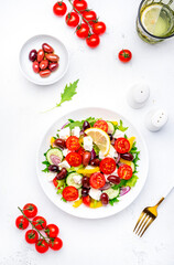 Mediterranean salad with vegetables, olives, cheese and lettuce, white background, top view