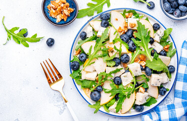 Salad with pear, blueberries, blue cheese, arugula and walnuts. White background, top view