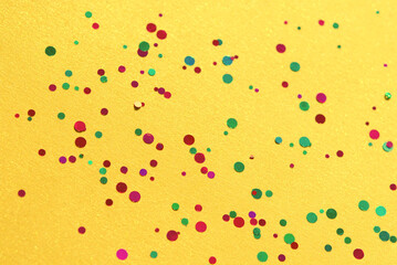 Colorful of confetti on yellow background. Brilliant colored sequins. Holiday greeting card. Happy holidays. Minimal, flat lay, copy space. Mockup