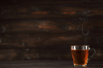 Glass cup of drink with steam on brown wooden table