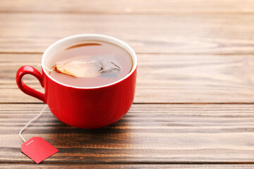 Cup of tea with tea bag on brown wooden table
