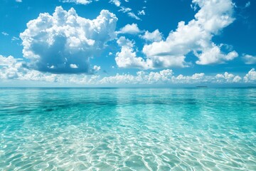 Obraz premium A serene scene of the clear blue sky and turquoise ocean, with fluffy white clouds in the background. The water is crystal clear, reflecting the vibrant colors of the sky above it. 