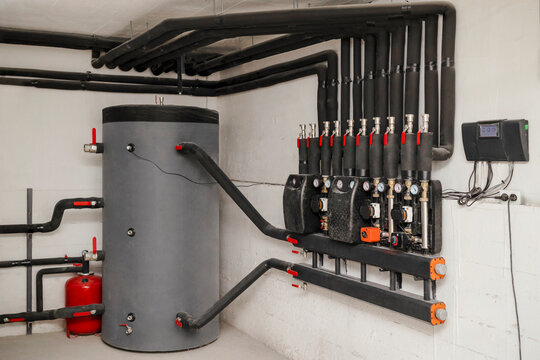 Heat Buffer Tank with Pipes for Heating System. Hot Water Tank Pressure Tank with Heat Exchanger of Solid Fuel Boiler. Hot Water Boiler System Tank in Boiler Room.